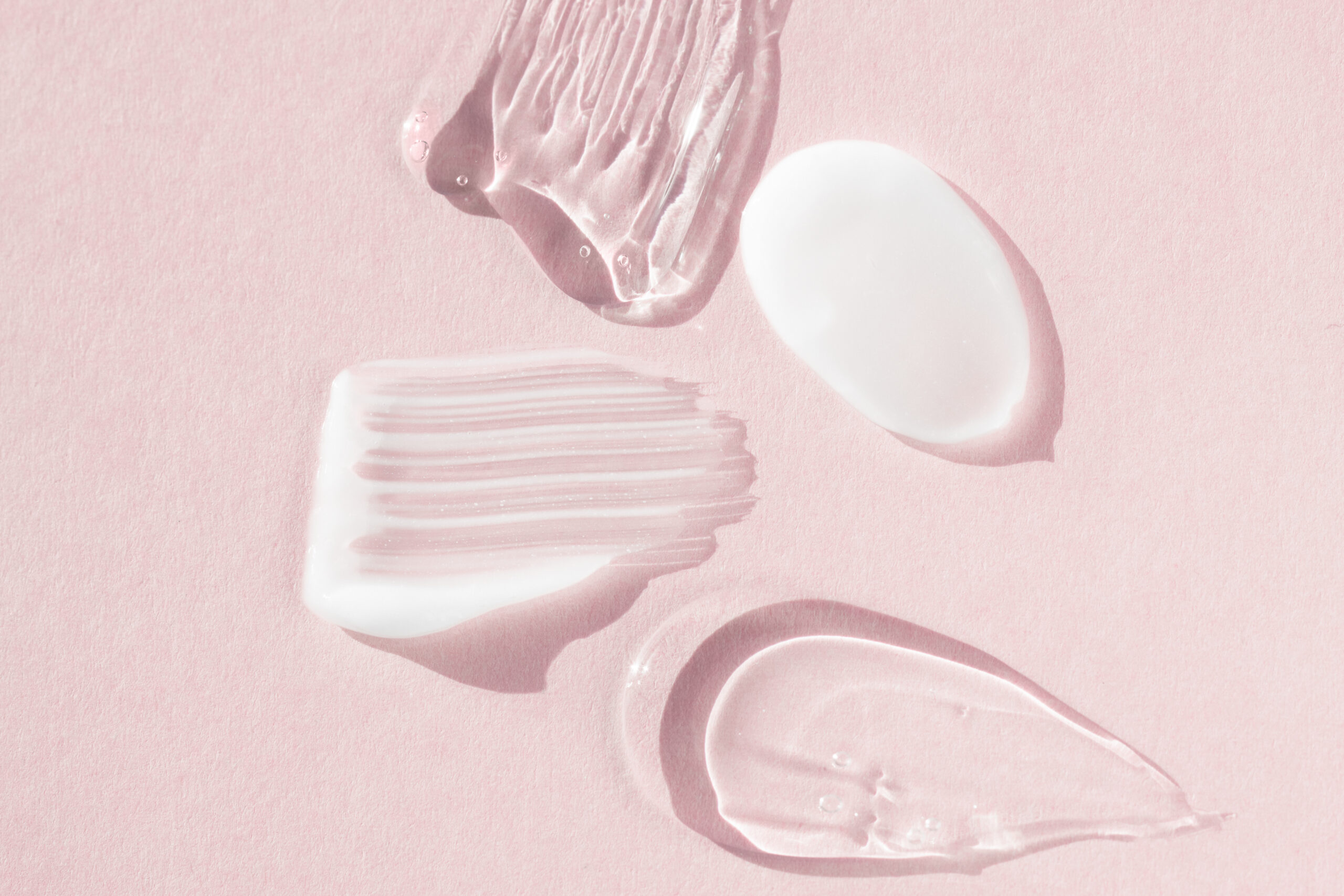 Cream and hyaluron samples, smears on a pink background. Dermatological and cosmetic product, macro. Cream and hyaluron samples, smears on a pink background. Dermatological and cosmetic product, macro.
